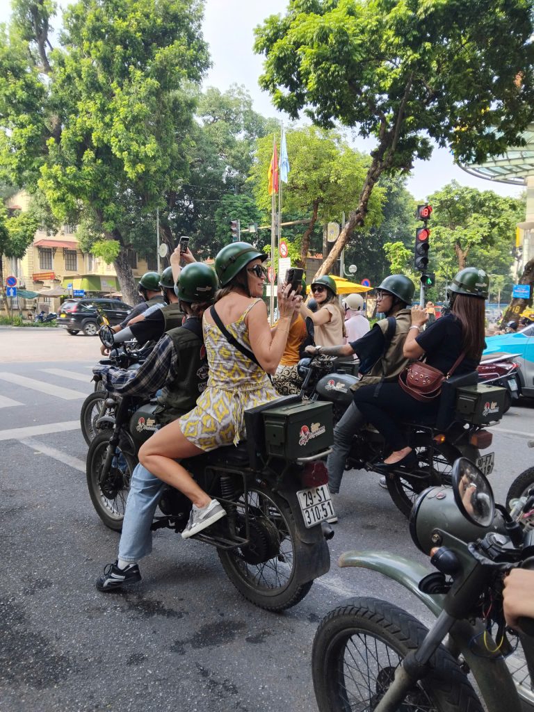 "Tourist riding on the back of a vintage Minsk motorbike through Hanoi backstreets with local guide"