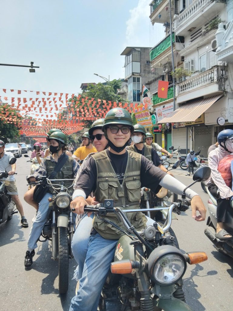 "Tourist riding on the back of a vintage Minsk motorbike through Hanoi backstreets with local guide"