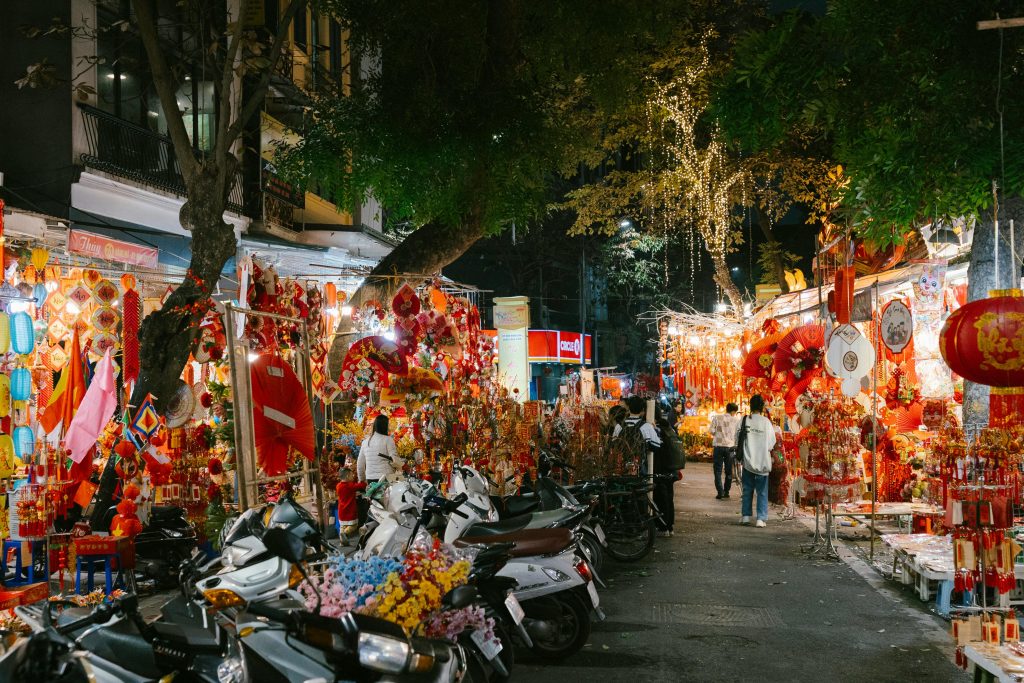Tourists walking through Hanoi Old Quarter narrow streets lined with traditional shops