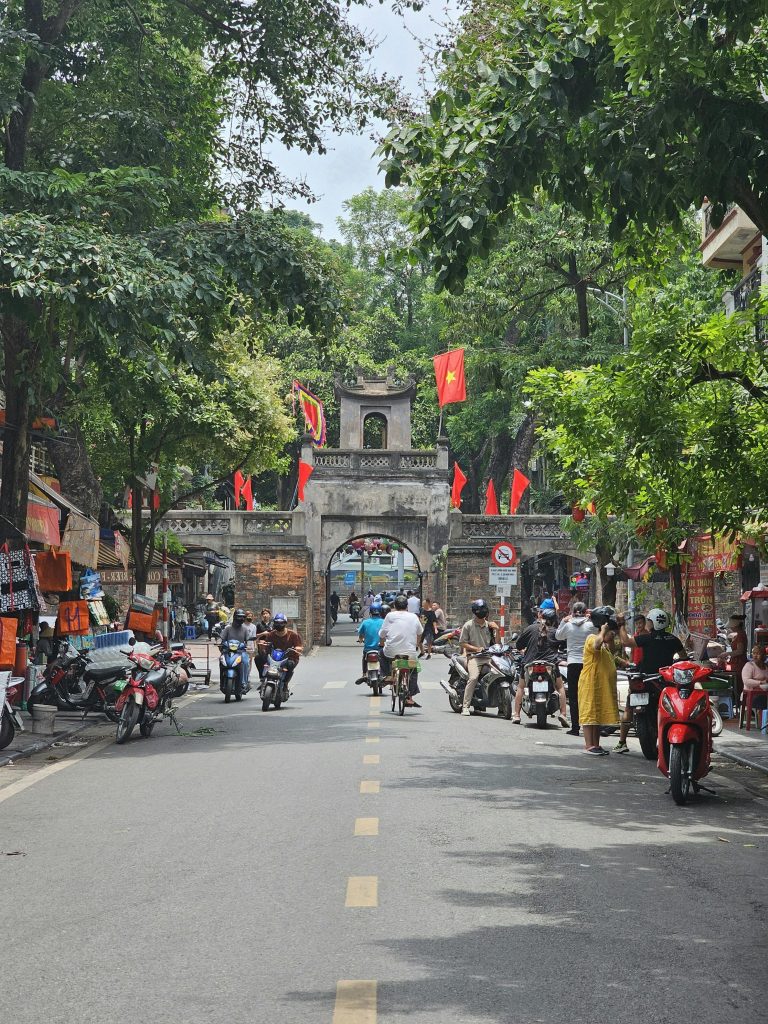 Tourists walking through Hanoi Old Quarter narrow streets lined with traditional shops