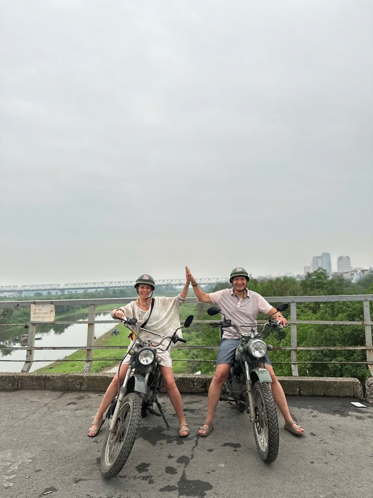 Couple enjoying panoramic views from Long Bien Bridge during a Hanoi Motorbike Tour.