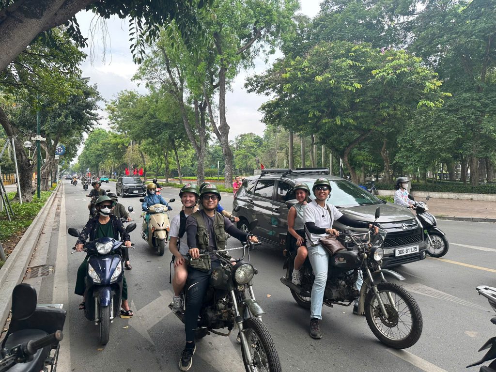 "Guests riding vintage Minsk motorcycles through Hanoi city streets"